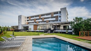 Un hôtel moderne doté d’une piscine, d’un espace extérieur aménagé et d’un patio couvert.