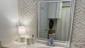 A bathroom with a white vanity, a large mirror, a sink, and a toilet. - Discover Mississippi State U within 4 mins! Cozy 1-bedroom awaits. (Starkville)