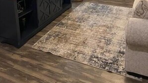 A living room with a dark wooden entertainment unit, a grey sofa, a patterned rug, and a hanging light fixture. - Discover Mississippi State U within 4 mins! Cozy 1-bedroom awaits. (Starkville)