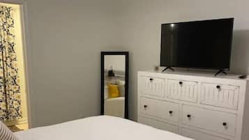 A bedroom with a bed, a dresser, a television, and a ceiling fan.