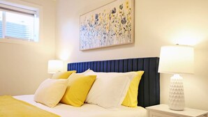 Ein Hotelzimmer mit einem Bett, zwei Nachttischlampen, einem Nachttisch und einem Gemälde an der Wand.