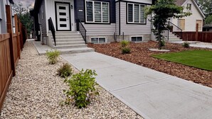 A modern two-story house with a front porch, a driveway, and a well-maintained lawn.