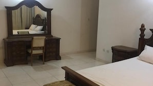 A bedroom with a bed, a wooden bench, a desk with a chair, and a mirror. - 3 Bed House - Sleeps 9 - Pets - Garden - Parking (Accra)