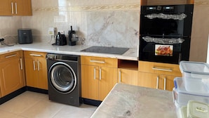 A kitchen with a washing machine, a coffee maker, a blender, a refrigerator, and a microwave. - 3 Bed House - Sleeps 9 - Pets - Garden - Parking (Accra)