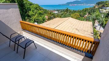 A balcony with a tiled floor, a wooden railing, and two chairs.