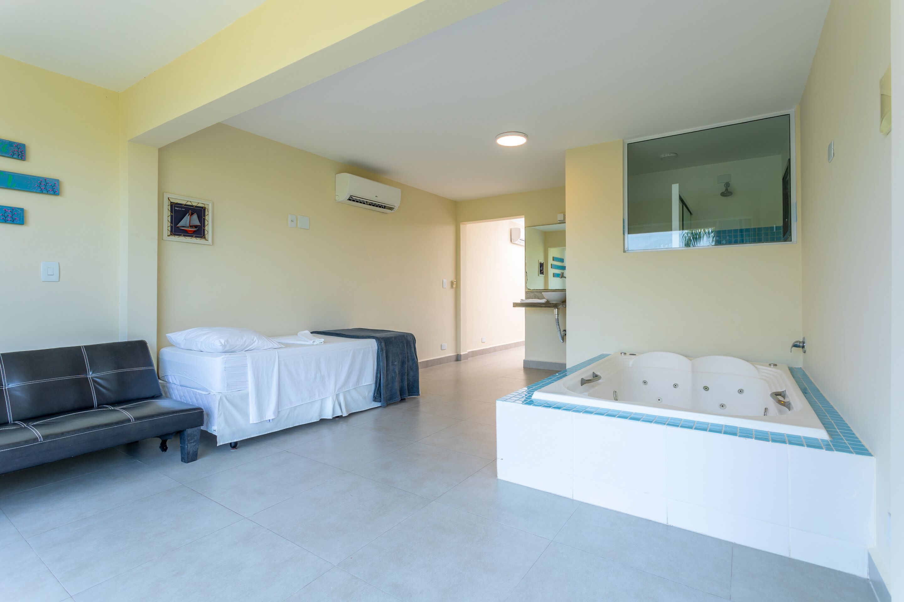 Une chambre d’hôtel avec un lit, un canapé, une baignoire et un miroir.