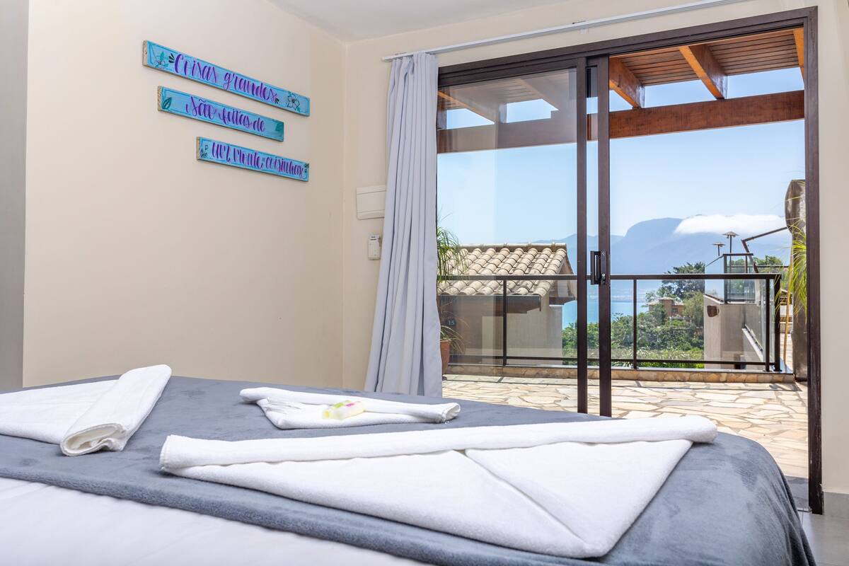 A hotel room with a bed, towels, and a balcony with a view.