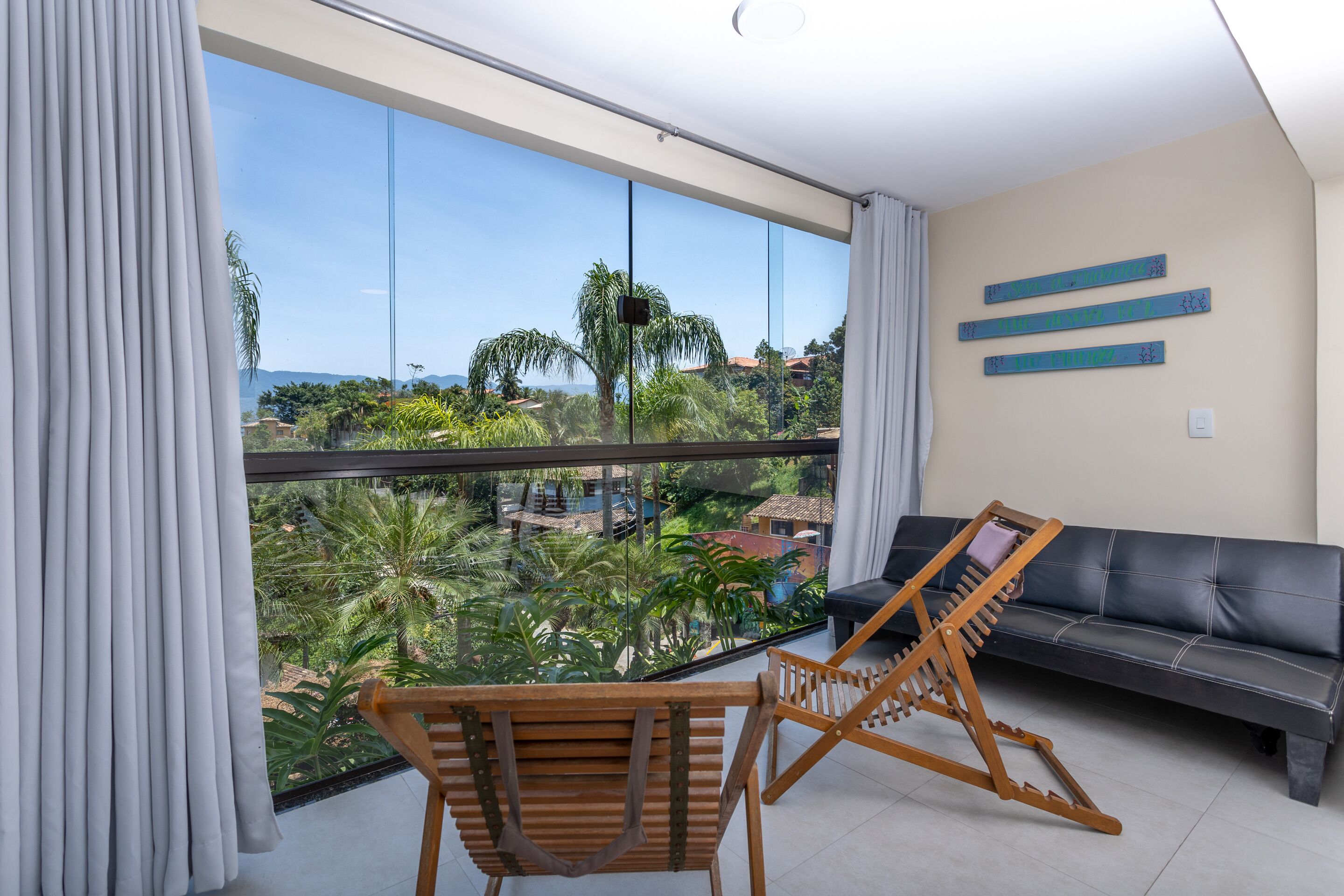Un salon moderne doté d’un grand balcon, d’un canapé et de chaises en bois.