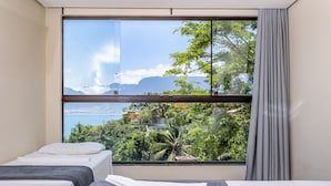 A room with two beds, a large window with a view of mountains and greenery. - Eco Baepi Residence (Ilhabela)