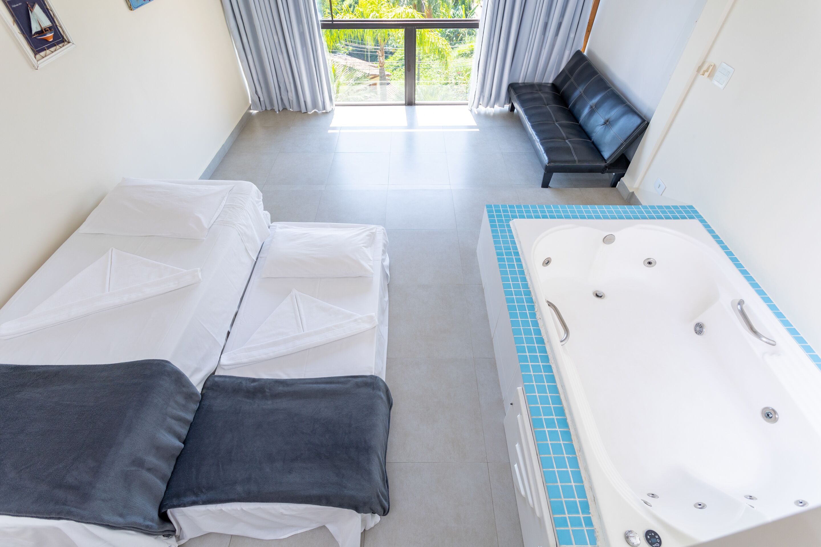 Habitación de hotel con una bañera grande, un sofá y dos camas.
