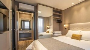 Una habitación de hotel moderna con una cama grande, un vestidor y un espejo.