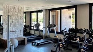 Un gimnasio con cintas de correr, máquinas de pesas y pesas sueltas.