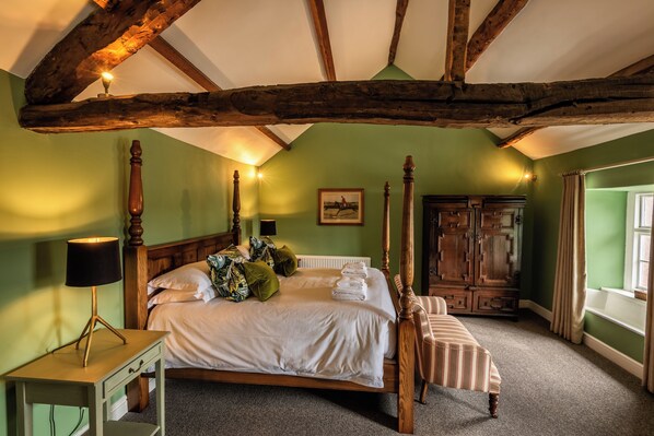 A bedroom with a four-poster bed, a wooden wardrobe, and a bedside table with a lamp. - Queen's Head Askham (Penrith)