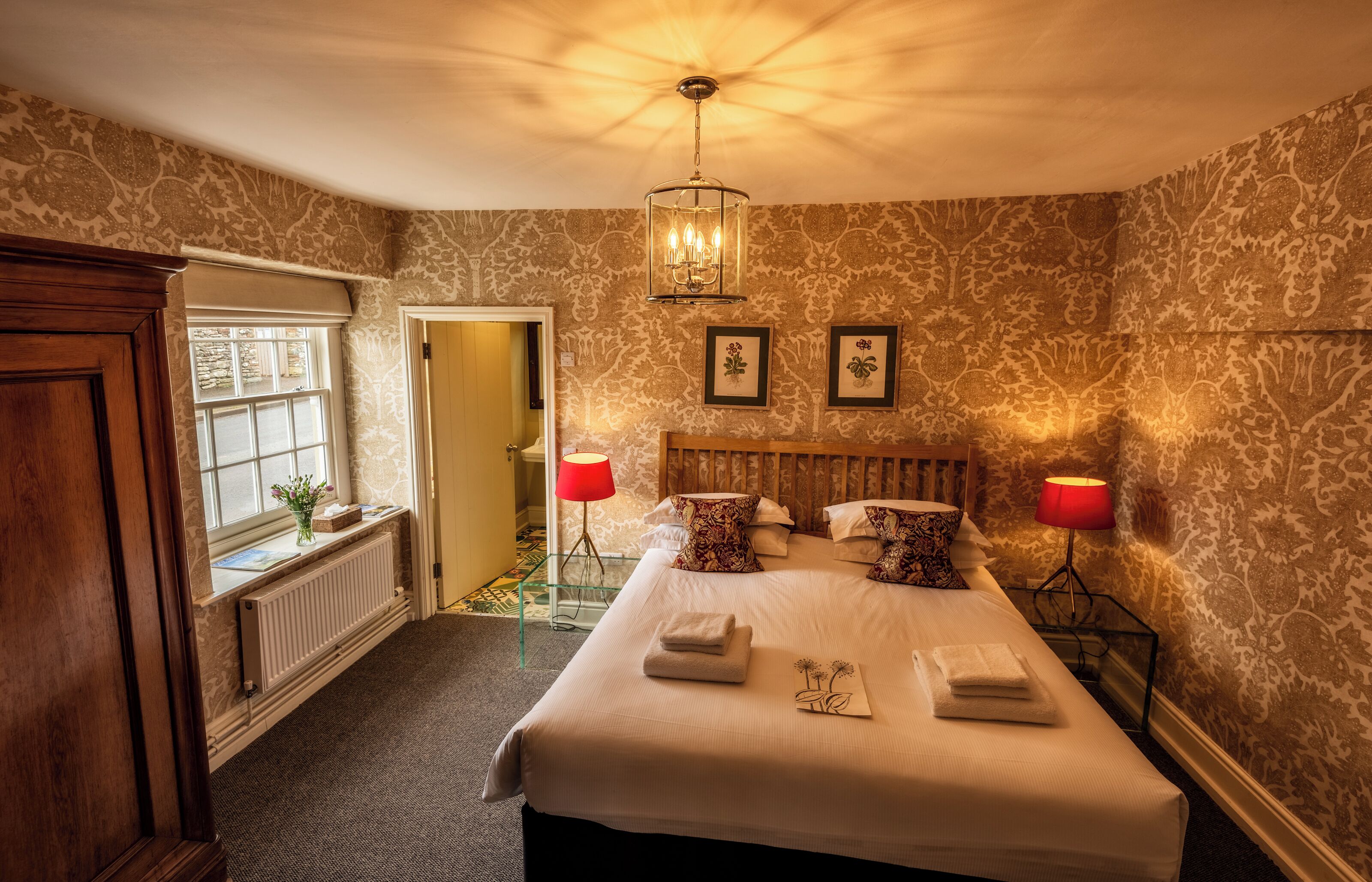 Une chambre à coucher bien aménagée, avec un grand lit, deux lampes de chevet et un lustre.