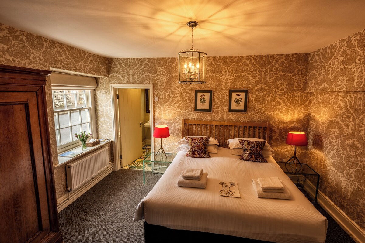 A neatly arranged bedroom with a large bed, two bedside lamps, and a chandelier.