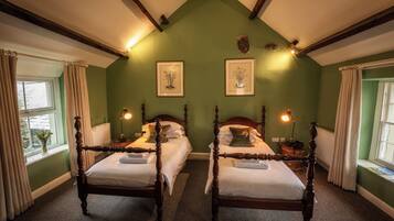 A room with two wooden beds, green walls, and a sloped ceiling with exposed beams.