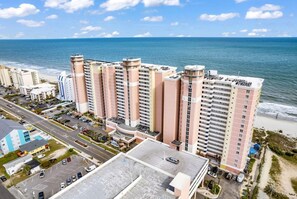 Um hotel moderno com vários andares, estacionamento e vista para a praia.
