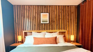A hotel room with a wooden slat wall, a bed with white and brown bedding, two bedside lamps, and a framed picture above the bed. - Sleek Urban Retreat in Happy Valley (Happy Valley)