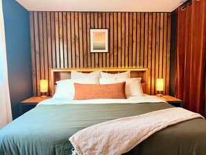 A hotel room with a wooden slat wall, a bed with white and brown bedding, two bedside lamps, and a framed picture above the bed. - Sleek Urban Retreat in Happy Valley (Happy Valley)