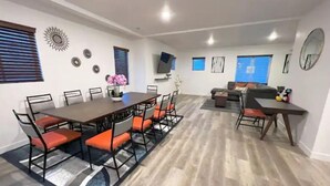 A spacious living area with a dining table, chairs, a sofa, and a TV. - Modern Townhouse w/ All Kings and Private Rooftop (West Valley City)
