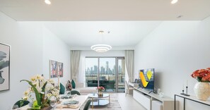 A modern living room with a dining area, large windows, and a city view.
