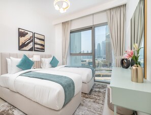 A hotel room with two beds, a large window with a city view, a desk, and a vase with flowers. - Vogue, Downtown with Easy Access to Dubai Mall (Dubai)