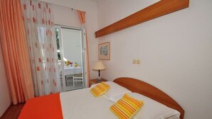 Ein Schlafzimmer mit Bett, Nachttisch, Lampe und einem Fenster mit Vorhängen.