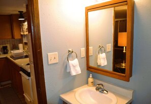 A bathroom with a sink, mirror, and towel rack. - Studio 7: Charming Studio Apartment Near Riverside Park in Grand Forks, ND (Grand Forks)