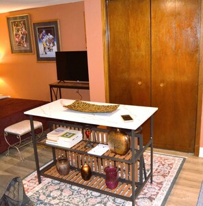 A room with a white table, a television, a wooden door, and a patterned rug. - Studio 7: Charming Studio Apartment Near Riverside Park in Grand Forks, ND (Grand Forks)