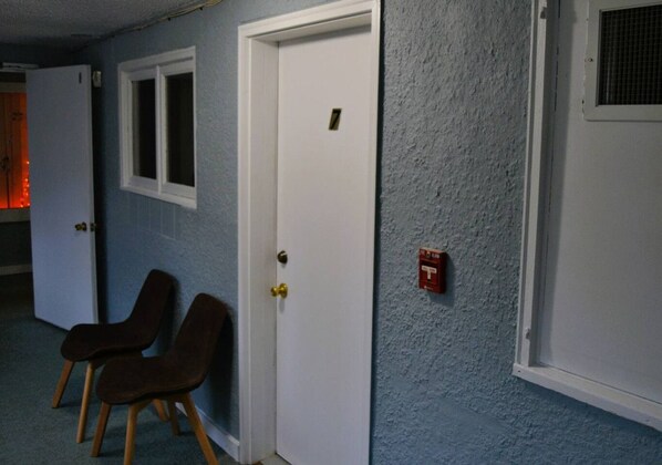 A hallway with two doors, a window, and a fire alarm.