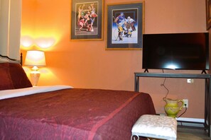 A hotel room with a bed, a TV, and two framed pictures on the wall. - Studio 7: Charming Studio Apartment Near Riverside Park in Grand Forks, ND (Grand Forks)