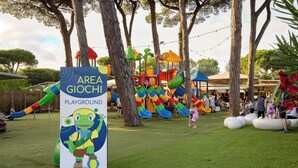 A playground area with slides and a sign featuring a cartoon character.