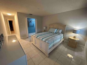 Quarto com cama, mesas de cabeceira e abajur.