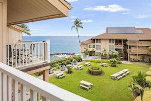 A hotel courtyard with a pool, lounge chairs, and a view of the ocean.