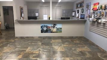 A reception area with a counter, a painting, and a wall with framed pictures.