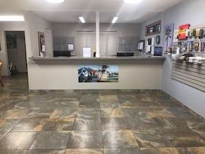 A reception area with a counter, a painting, and a wall with framed pictures. - Sea Village (Kailua-Kona)