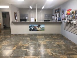 Un área de recepción con mostrador, un cuadro y una pared con fotografías enmarcadas.