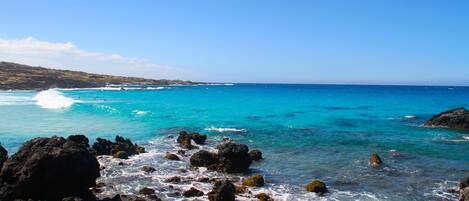 A coastal landscape with rocky terrain and clear blue waters.