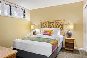 A hotel room with a bed, two bedside lamps, a headboard, and a window with blinds. - Sea Village (Kailua-Kona)