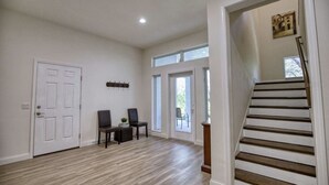 A spacious room with hardwood flooring, a white door, a staircase, and a small table with chairs. - Waterfront Oasis and Boaters Paradise! Coastal style home with Boat Dock! 🚤🎣 (Englewood)