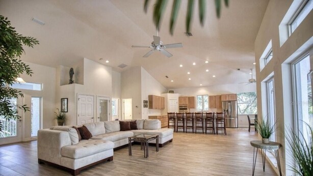 A spacious living room with a sectional sofa, a dining area with a high table, and a kitchen in the background. - Waterfront Oasis and Boaters Paradise! Coastal style home with Boat Dock! 🚤🎣 (Englewood)