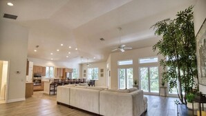 A spacious living area with a large sofa, a dining table, and a kitchen in the background. - Waterfront Oasis and Boaters Paradise! Coastal style home with Boat Dock! 🚤🎣 (Englewood)