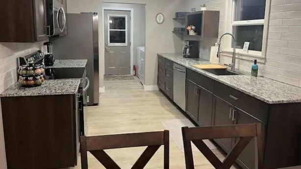 A kitchen with dark cabinets, a granite countertop, and a wooden dining table.