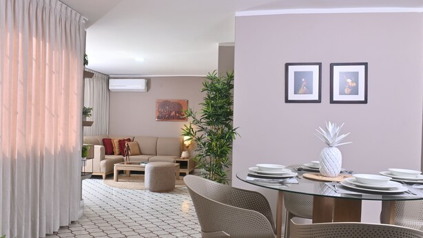 A modern living room with a dining area, featuring a round glass table, beige chairs, and a pineapple centerpiece. - Apartahotel de lujo en Barranquilla x5 personas - Apto 301 (Barranquilla)