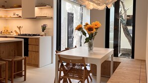 Una cocina moderna con una isla central, sillas de madera, una mesa de comedor blanca y un jarrón con girasoles.
