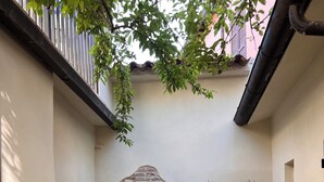 Un patio con muro de piedra, fuente de agua y diferentes plantas.