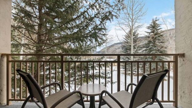 A balcony with two chairs and a table, overlooking a snowy landscape with trees and a mountain. - The Wren Studio VAIL WALK toLIFT (Vail)
