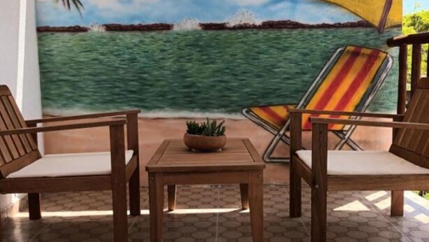 An outdoor seating area with wooden furniture and a hexagonal tile floor.