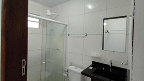 A bathroom with a glass shower enclosure, a white toilet, and a black sink with a mirror above it.