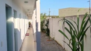 A corridor with a tiled floor, white walls, and a clear blue sky.